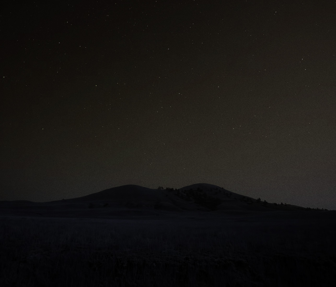 a night photo of a field and hills